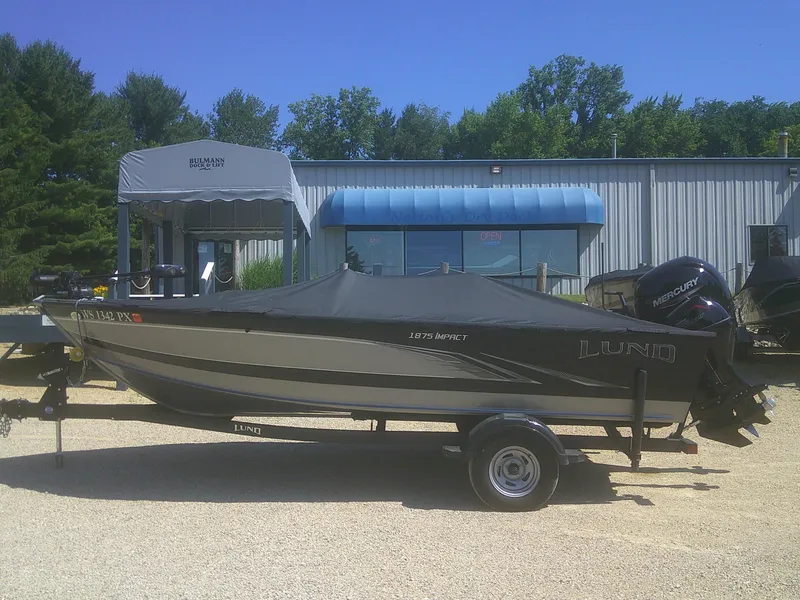 Slide: The Image of 2020 Lund 1875 Impact SS boat on trailer, covered, outside dealership. - 19