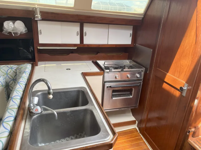 Slide: The Image of 1989 Catalina 34 MkII yacht kitchen with stove, sink, and wooden cabinetry. - 10