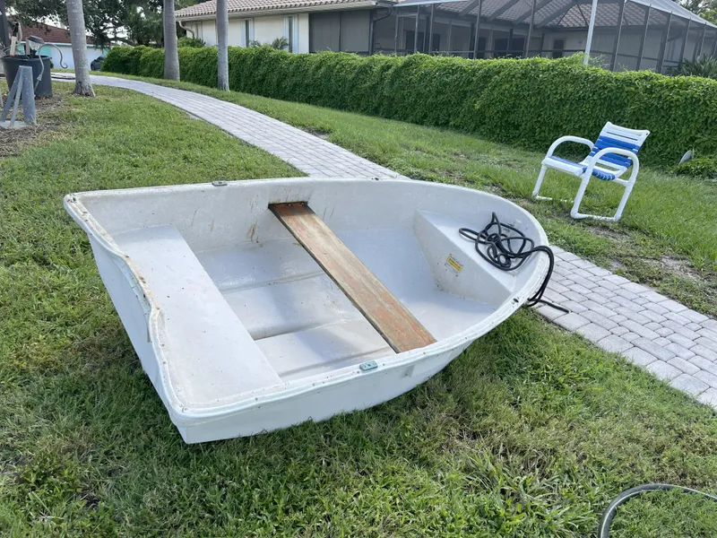 Slide: The Image of Small white dinghy on grass near a paved path, with a coiled rope inside. - 21