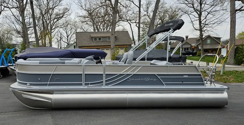 Slide: The Image of 2023 South Bay S224 UL TRIPLE pontoon boat in a residential area. - 2