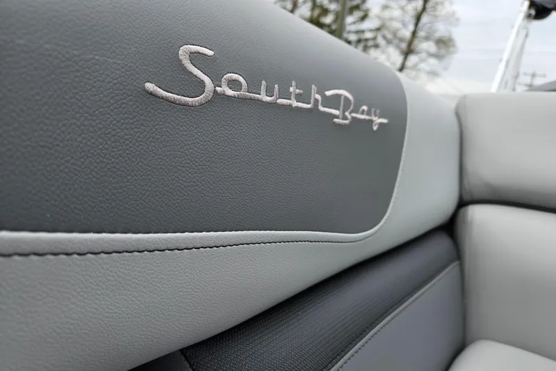 Slide: The Image of 2023 South Bay S224 UL TRIPLE boat interior, close-up of logo on grey upholstery. - 20