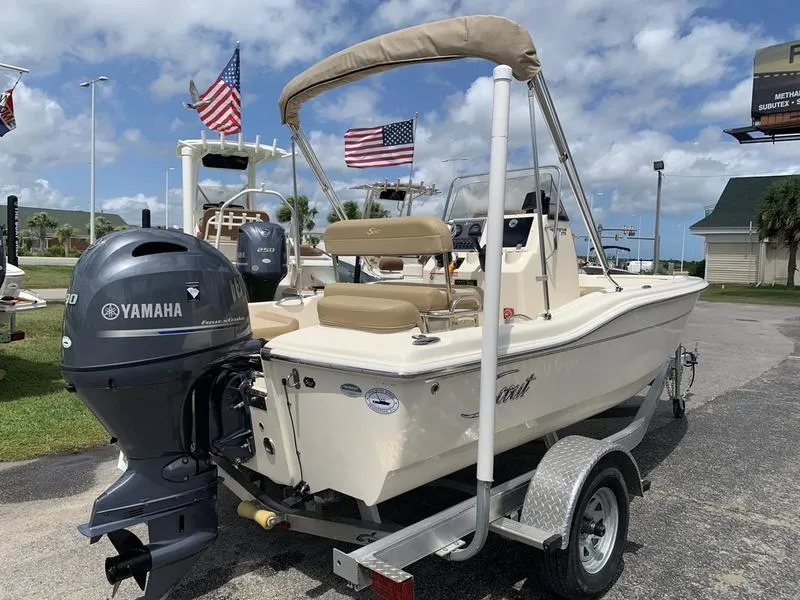 Slide: The Image of 2019 Scout 175 Sportfish boat with Yamaha engine on trailer, flags in background. - 4