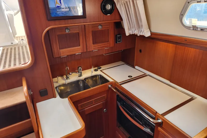 Slide: The Image of 2007 Hallberg-Rassy 37 yacht interior kitchen with wooden cabinets and stainless steel sink. - 33