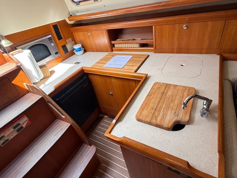 Slide: The Image of Compact kitchen in a 2005 Hunter 33 sailboat with wood cabinetry and modern appliances. - 10