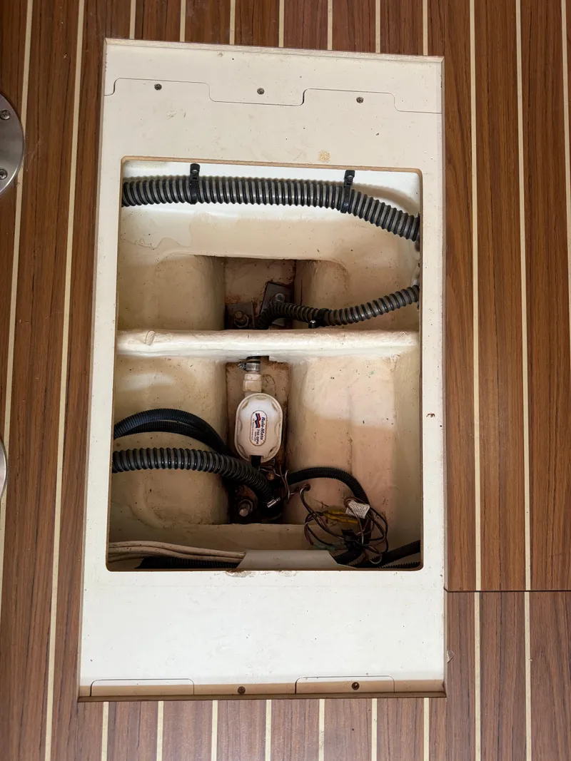 Slide: The Image of Bilge compartment of a 2005 Hunter 33 sailboat with visible hoses and pump. - 13