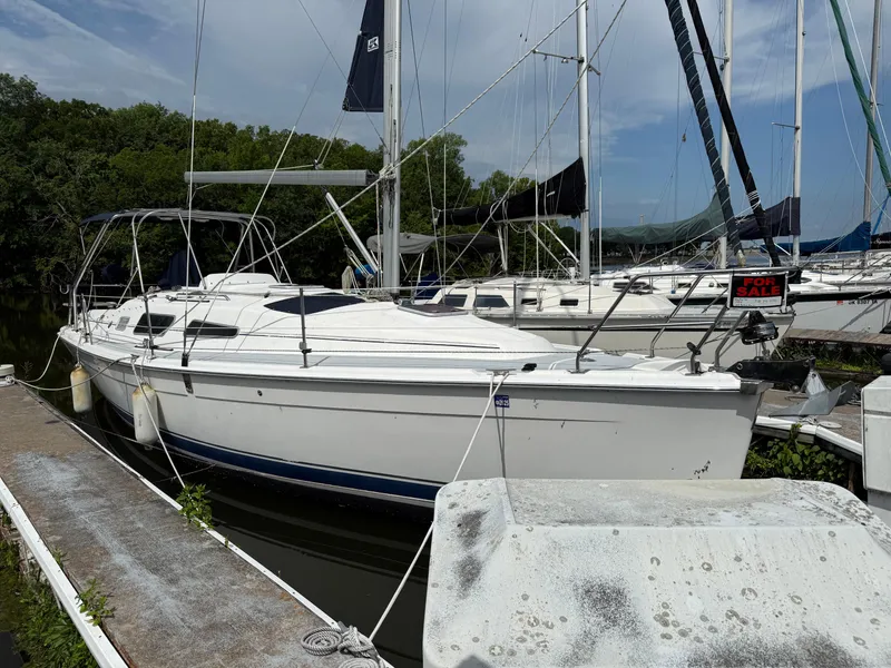 Slide: The Image of 2005 Hunter 33 sailboat docked, for sale, with lush greenery in the background. - 2