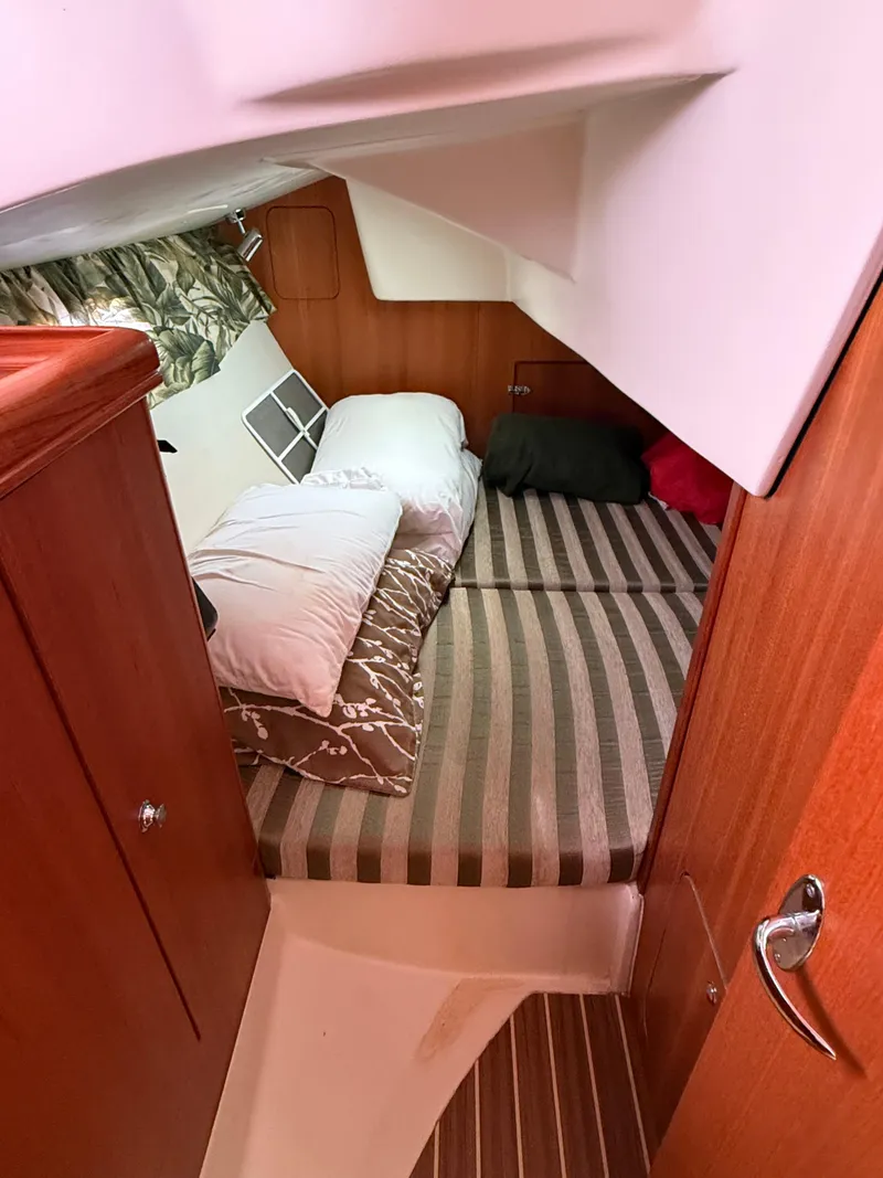 Slide: The Image of Cozy cabin interior of a 2005 Hunter 33 sailboat with striped bedding and pillows. - 9