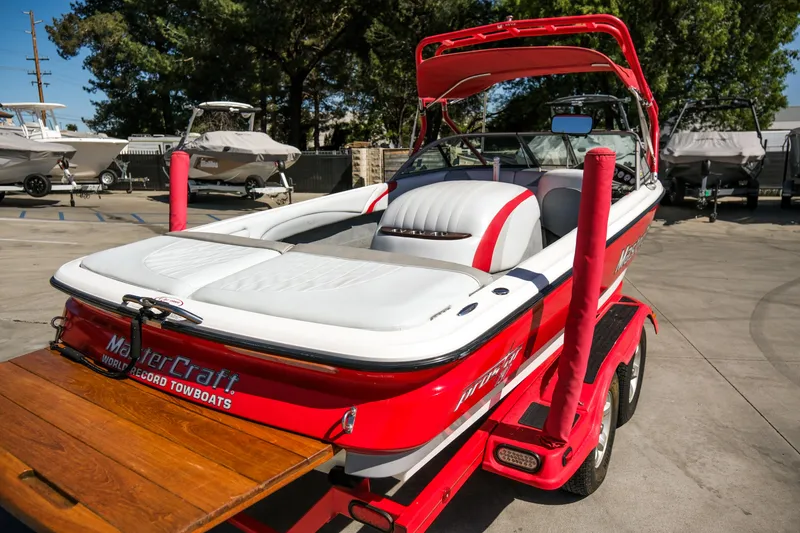 Slide: The Image of 2002 MasterCraft ProStar 197 boat, red and white, parked on a trailer in a marina. - 5