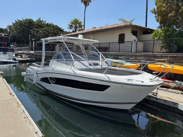 Slide: The Image of 2023 Jeanneau Leader 9.0 WA boat docked in a marina, surrounded by trees and buildings. - 2