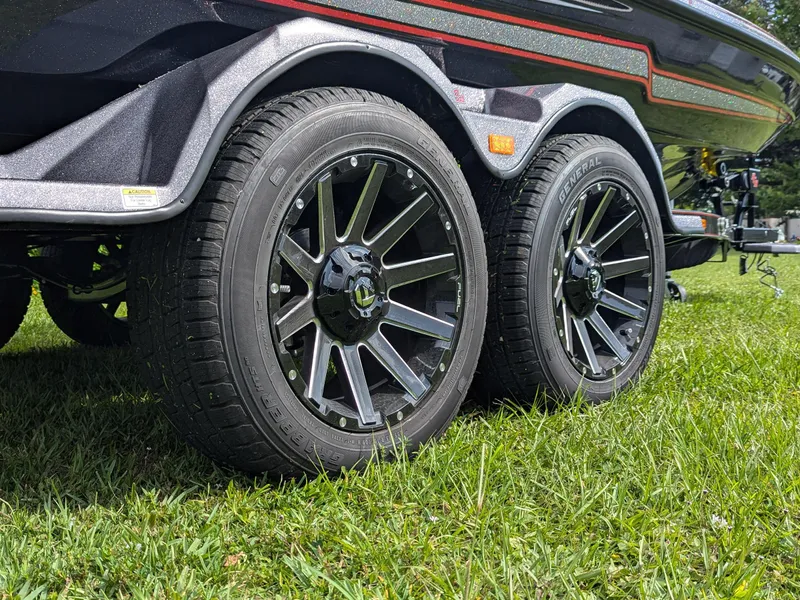 Slide: The Image of 2026 Bass Cat Lynx STS trailer wheels on grass, showcasing sleek design and durability. - 5
