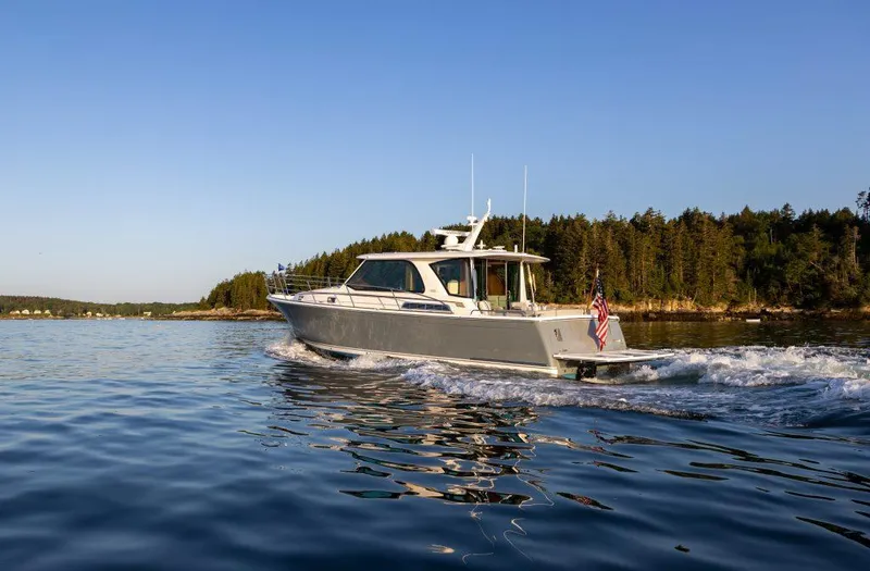 Slide: The Image of 2026 Sabre 43 Salon Express cruising on a serene lake with forested shoreline. - 2