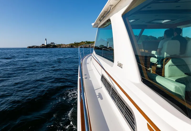 Slide: The Image of 2026 Sabre 43 Salon Express yacht cruising near a coastal lighthouse. - 7