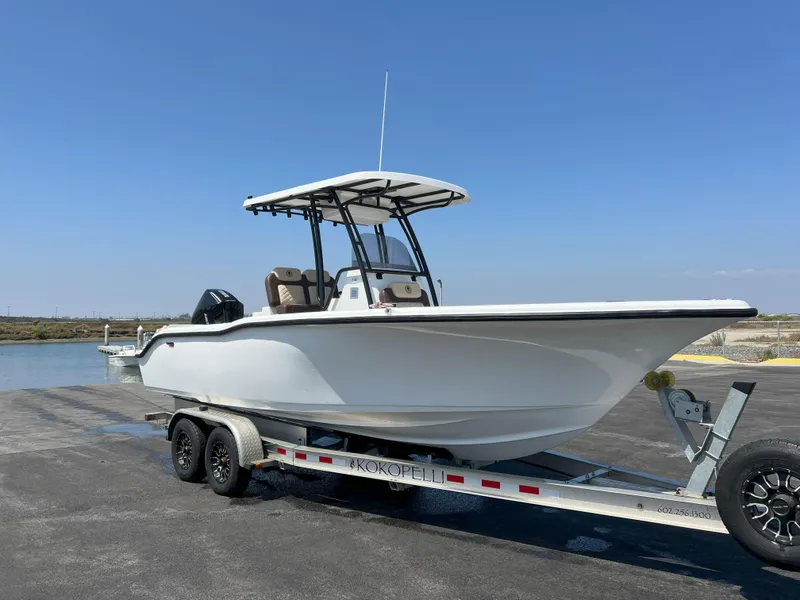 Slide: The Image of 2026 Reflex Gladiator 2400 boat on trailer by waterfront under clear blue sky. - 1
