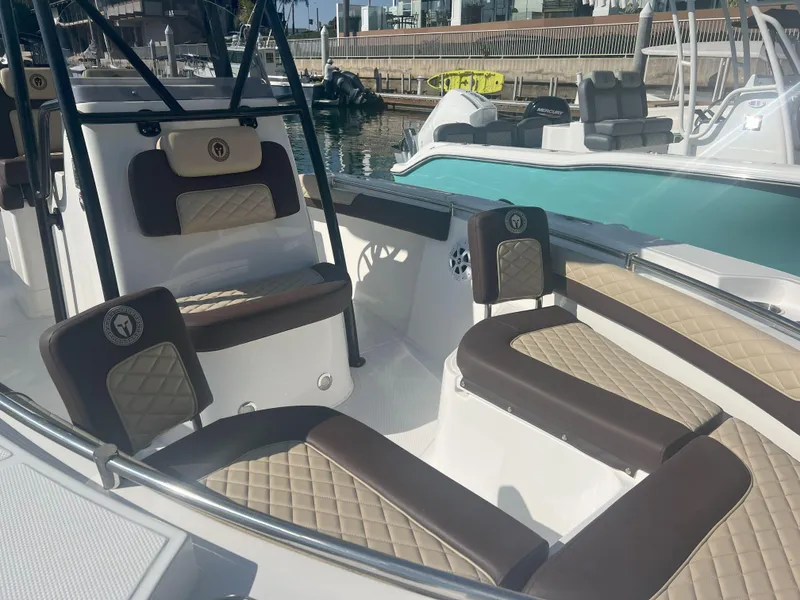 Slide: The Image of 2026 Reflex Gladiator 2400 boat interior with cushioned seating, docked at marina. - 11