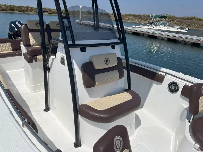 Slide: The Image of 2026 Reflex Gladiator 2400 boat interior with cushioned seating, docked by the water. - 45