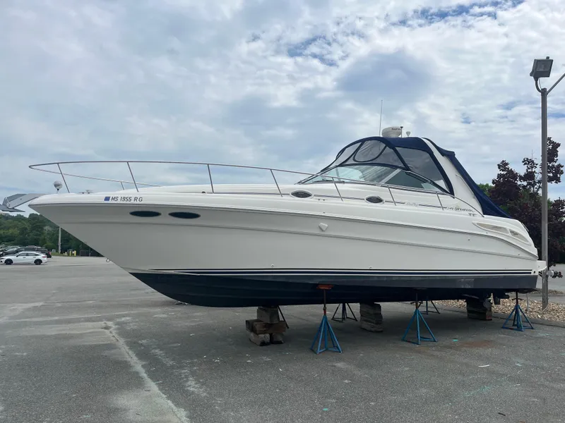 Slide: The Image of 2000 Sea Ray 340 Sundancer yacht on stands, parked outdoors under cloudy sky. - 10