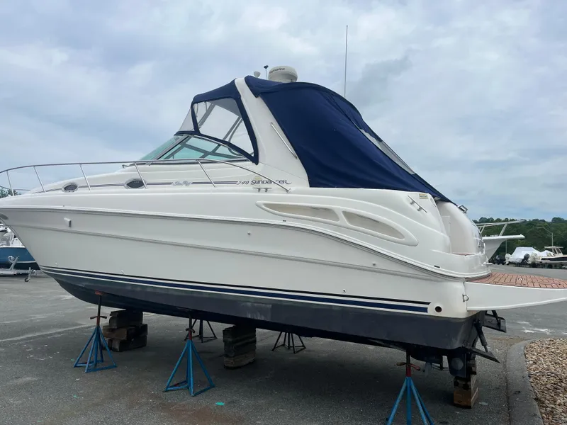 Slide: The Image of 2000 Sea Ray 340 Sundancer boat on stands, with blue cover, in a marina setting. - 11