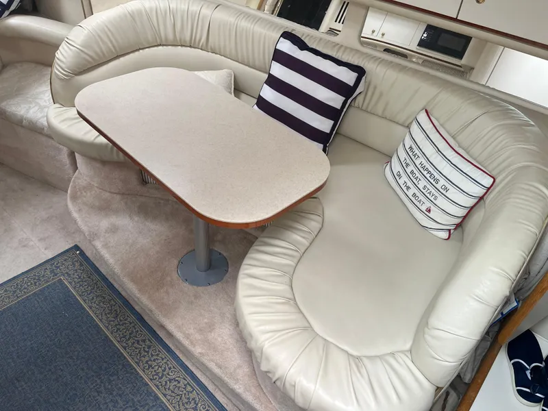 Slide: The Image of Interior of 2000 Sea Ray 340 Sundancer with cream leather seating and nautical-themed pillows. - 19