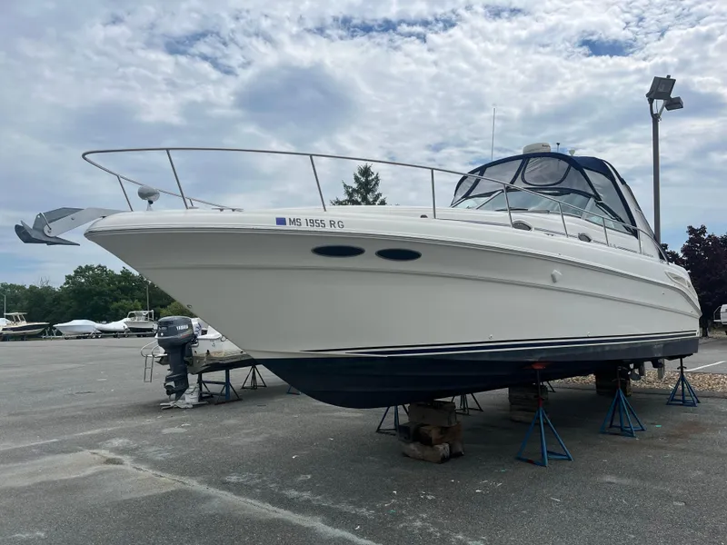 Slide: The Image of 2000 Sea Ray 340 Sundancer boat on stands, parked outdoors under cloudy sky. - 9
