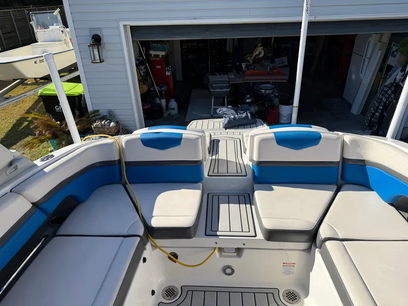 Slide: The Image of 2017 Chaparral Vortex 2430 VRX boat interior with blue and gray seating in a garage. - 10