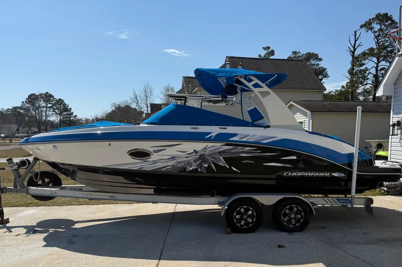 Slide: The Image of 2017 Chaparral Vortex 2430 VRX boat on trailer, blue and white design, parked outdoors. - 2