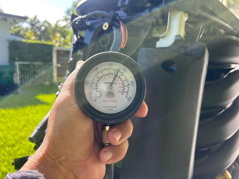 Slide: The Image of Hand holding a compression tester near a Robalo R222 engine, 2018 model. - 11