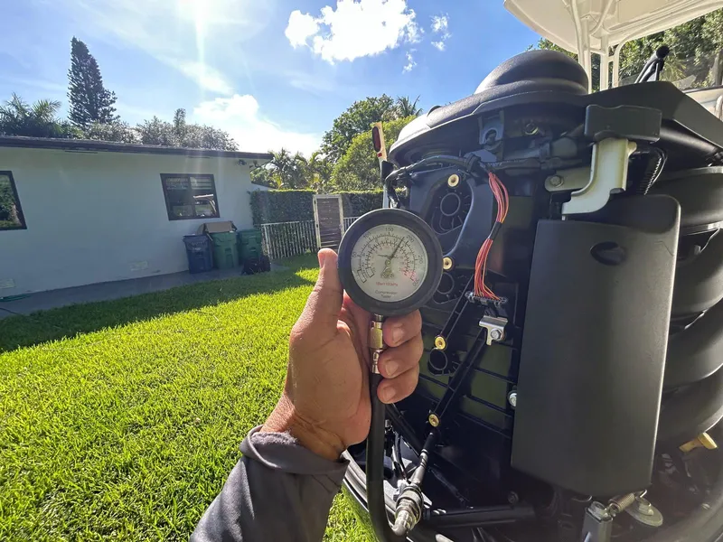 Slide: The Image of Hand holding pressure gauge near Robalo R222 boat engine, sunny backyard setting. - 12