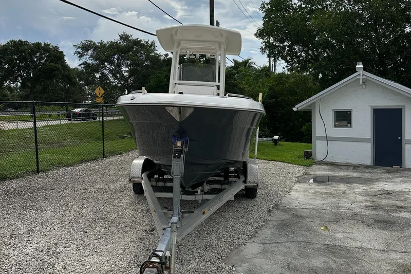 Slide: The Image of 2018 Robalo R222 boat on trailer, parked on gravel near a small white building. - 16