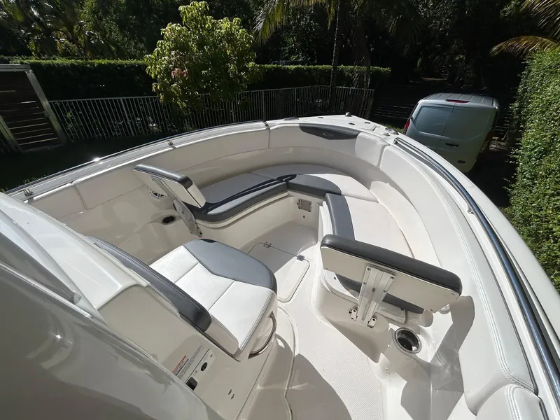 Slide: The Image of 2018 Robalo R222 boat interior with seating and cup holder, surrounded by lush greenery. - 9