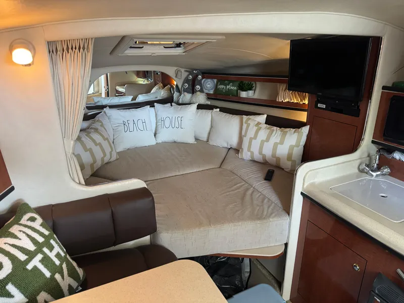 Slide: The Image of Interior of 2003 Sea Ray 280 Sundancer with cozy seating, pillows, and a small kitchenette. - 10