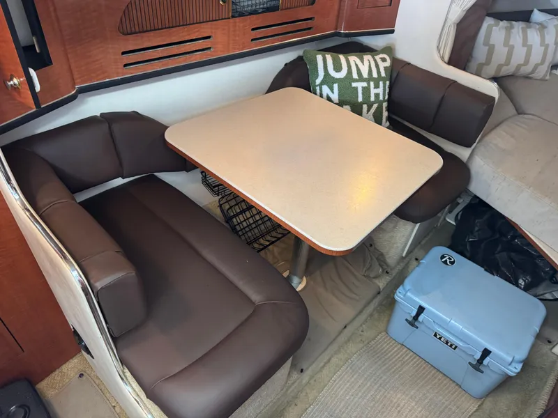 Slide: The Image of Interior of 2003 Sea Ray 280 Sundancer with dining area and cushioned seating. - 11