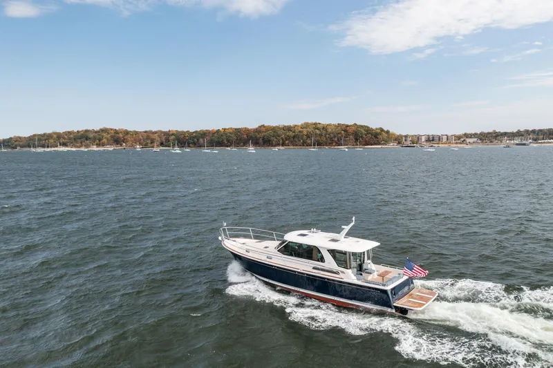 Slide: The Image of 2025 Sabre 43 Salon Express cruising on a scenic lake with autumn foliage. - 13