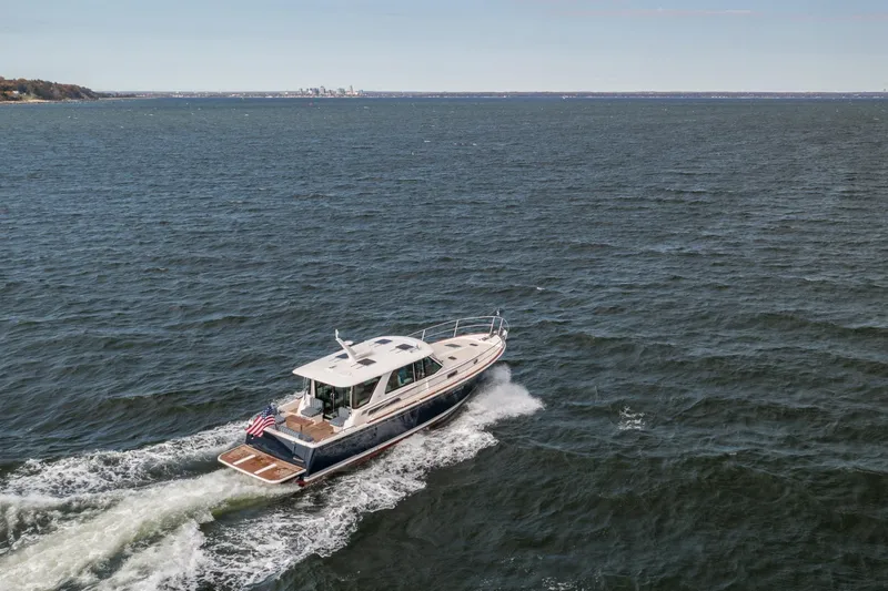 Slide: The Image of 2025 Sabre 43 Salon Express cruising on open water, displaying sleek design and American flag. - 15