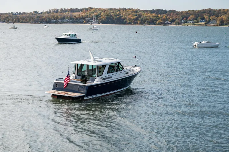 Slide: The Image of 2025 Sabre 43 Salon Express cruising on a scenic lake with other boats. - 17