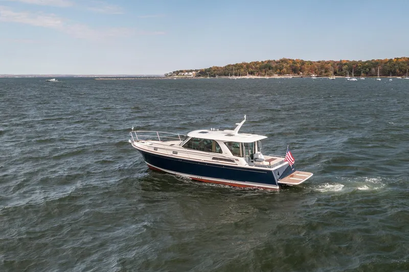 Slide: The Image of 2025 Sabre 43 Salon Express yacht cruising on a scenic lake with distant shoreline. - 2