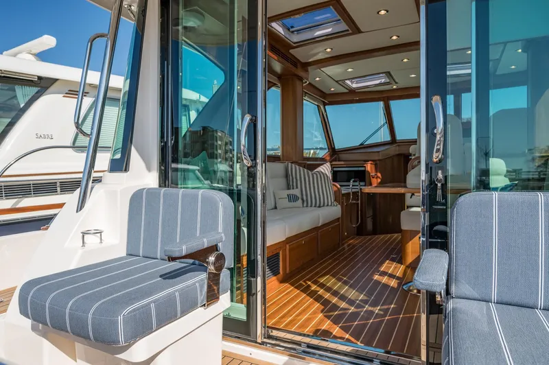 Slide: The Image of 2025 Sabre 43 Salon Express yacht interior with striped seating and wooden flooring. - 23