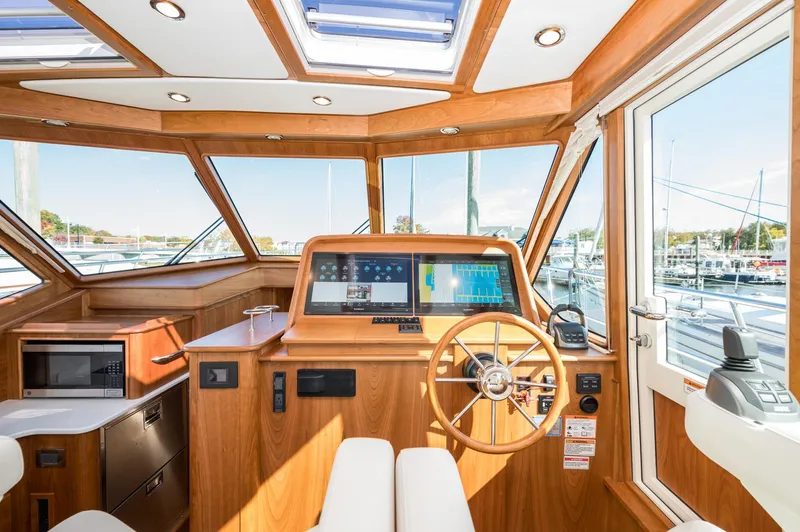 Slide: The Image of 2025 Sabre 43 Salon Express helm with modern navigation, wooden interior, and marina view. - 29