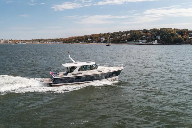 Slide: The Image of 2025 Sabre 43 Salon Express cruising on a scenic coastal waterway. - 4