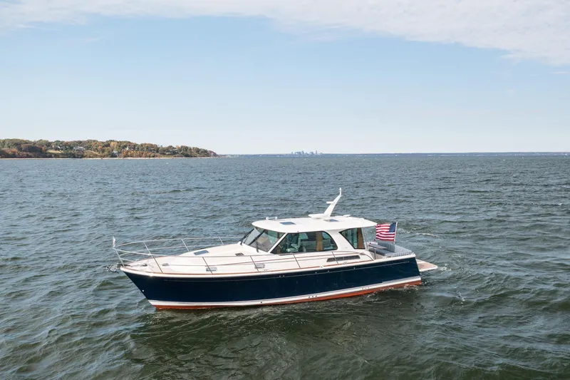 Slide: The Image of 2025 Sabre 43 Salon Express yacht cruising on open water with distant shoreline. - 6