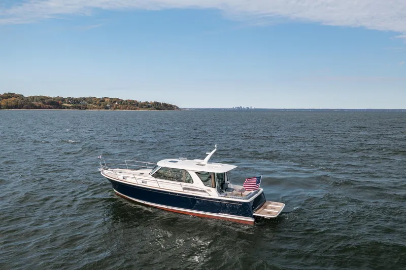 Slide: The Image of 2025 Sabre 43 Salon Express yacht cruising on open water with distant shoreline. - 7