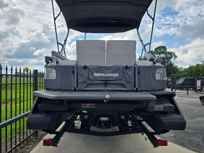 Slide: The Image of 2023 Sea-Doo Switch Sport 21 boat, rear view, parked outdoors under cloudy sky. - 5