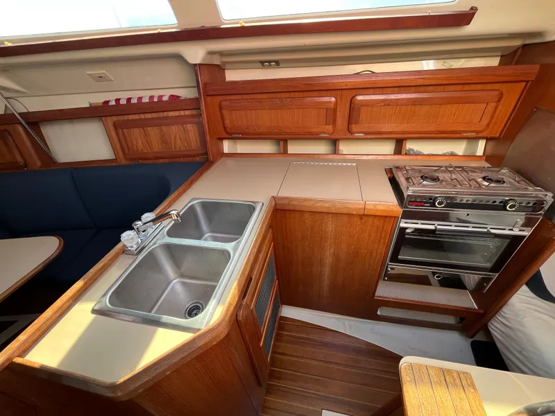 Slide: The Image of 1992 Hunter 30-2 yacht interior kitchen with stove, sink, and wooden cabinetry. - 2