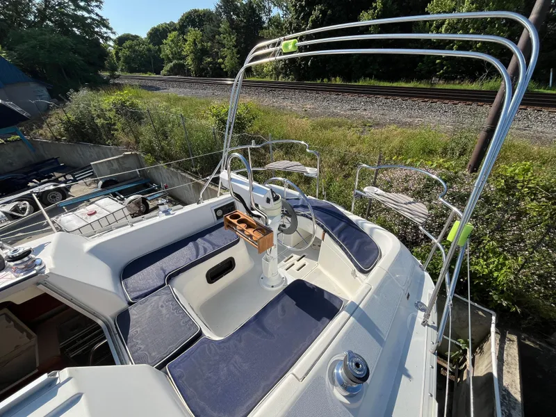 Slide: The Image of 1992 Hunter 30-2 sailboat cockpit with blue cushions and steering wheel, near railway tracks. - 20
