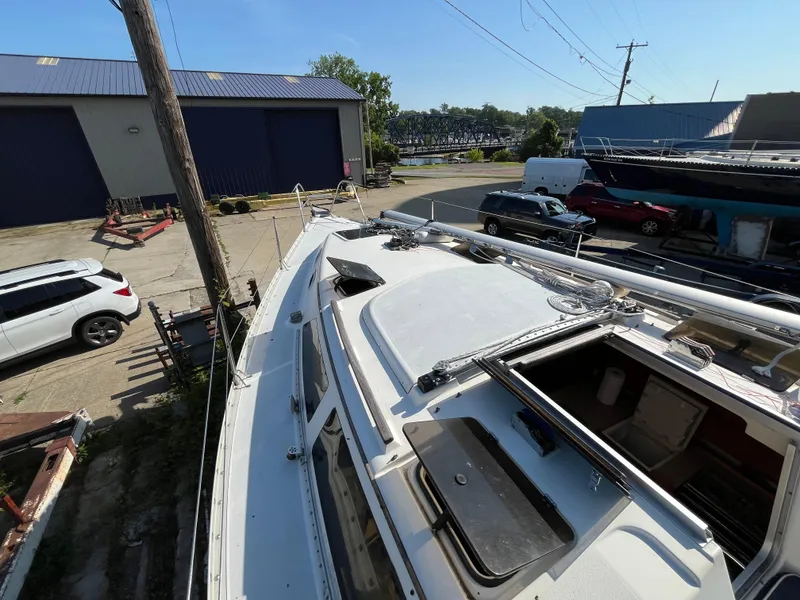 Slide: The Image of Hunter 30-2 sailboat from 1992 in a boatyard, surrounded by vehicles and buildings. - 21