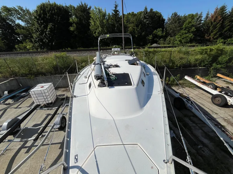 Slide: The Image of 1992 Hunter 30-2 sailboat on land, surrounded by greenery and equipment. - 24