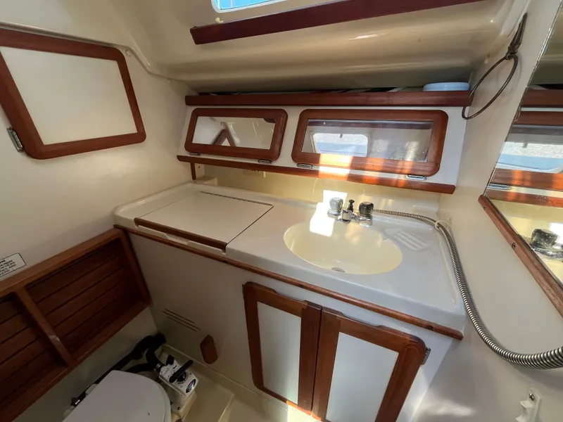 Slide: The Image of 1992 Hunter 30-2 yacht bathroom with sink, wooden cabinets, and mirror. - 8