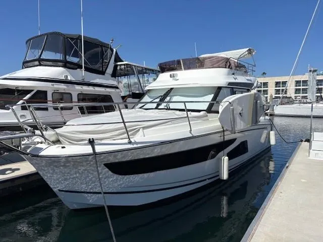 Slide: The Image of 2020 Jeanneau NC 1095 Fly yacht docked at marina under clear blue sky. - 2