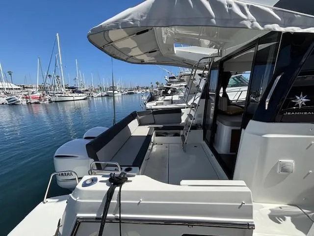 Slide: The Image of 2020 Jeanneau NC 1095 Fly yacht docked in marina, featuring spacious deck and seating area. - 29