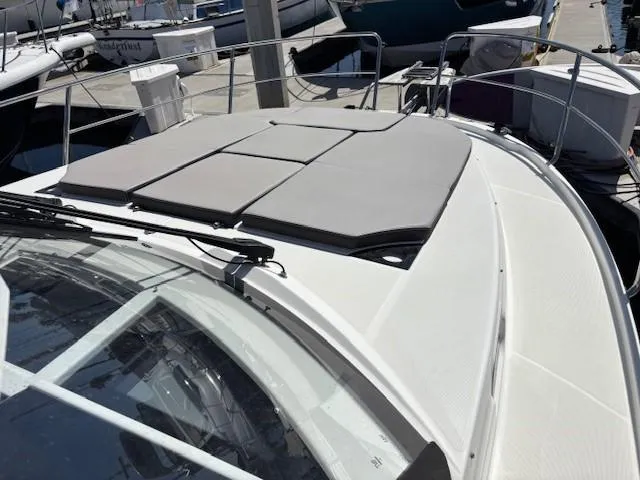 Slide: The Image of 2020 Jeanneau NC 1095 Fly yacht with sunbathing cushions on deck, docked at marina. - 4
