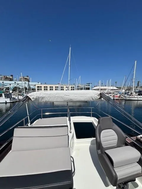Slide: The Image of 2020 Jeanneau NC 1095 Fly yacht at marina, featuring flybridge seating and clear blue sky. - 46